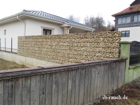 Ältere Holzzaum und eine Trockenmauer als Grundstückgrenze